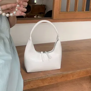 Detail shot of a white patent soft leather hobo bag with dual zippers on wooden table display.