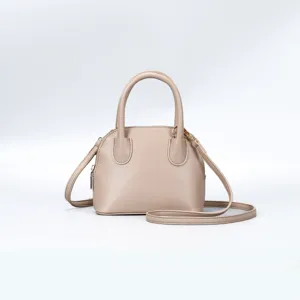 Close-up of stylish beige dome handbag texture, metal zipper and shoulder strap details.
