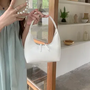 Minimalist white soft leather hobo underarm bag, sleek crescent shape with zipper closure.
