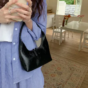 Detailed shot of a stylish black glossy hobo bag with crescent design and soft leather texture.