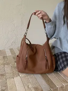 Retro brown textured hobo shoulder bag with dual zipper pockets and stylish tassels.