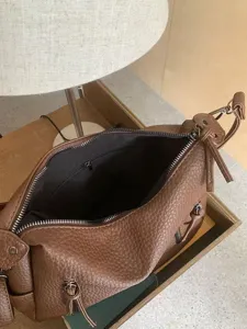 Brown leather shoulder bag interior detail showing spacious compartment and zippered pocket.