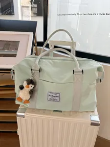 Large capacity travel duffel bag with cute penguin pendant, light green fitness bag.