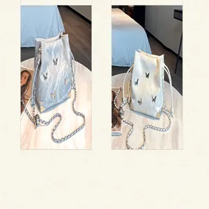 Silver 3D butterfly bucket bag with metal chain strap and drawstring closure for women.