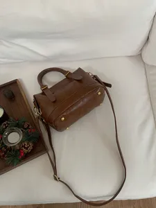 Detailed view of a retro brown leather bowling handbag, casual shoulder crossbody bag lifestyle.