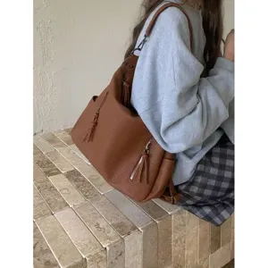 Detail shot of retro brown leather shoulder bag with tassels and zipper, stylish commuter accessory.