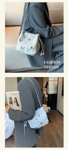 Detailed view of the trendy silver bucket bag featuring 3d butterflies and chic metal chains.