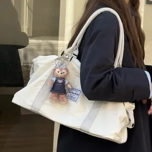 Large capacity canvas travel bag with cute plush pendant, lightweight and stylish daily tote.