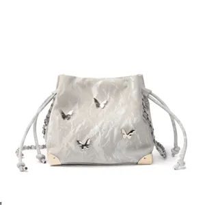 Silver bucket bag with 3d butterflies, drawstring closure, and metal chain shoulder strap.