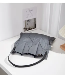Detail view of grey geometric pleated canvas shoulder bag, minimalist aesthetic design.