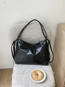 Detail shot of black soft leather hobo shoulder bag on textured chair with bagel prop.