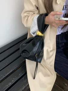 Λεπτομερής όψη μαύρης σούρωσης τσάντας σύννεφου με χρυσή σφαίρα, κομψή τσάντα.