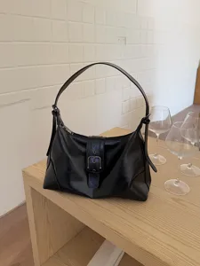 Close-up of black PU leather shoulder bag detail on wooden table, vintage style aesthetic.