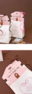 Sacchetti regalo a forma di casa con etichetta superiore e nastri per biscotti e dolci.