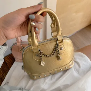 Gold metallic shell handbag for women with chic metal rivets and dice chain charm daily use.