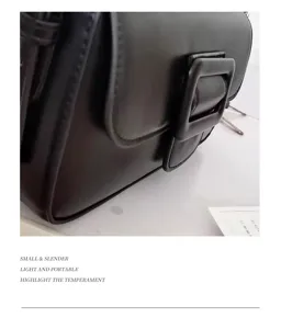 Detailed view of the black leather shoulder bag featuring a chunky buckle and clean design.