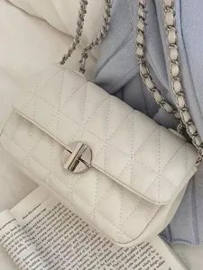 White quilted chain shoulder bag, elegant flap design with metal lock for women commuting.
