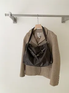 Detail shot of a dark brown retro soft leather hobo shoulder bag hanging on a wool blazer.