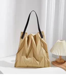 Detailed view of pleated canvas tote bag showing geometric texture and sturdy black shoulder straps.