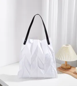 Detail view of a white pleated canvas tote bag with black shoulder straps for daily commute.
