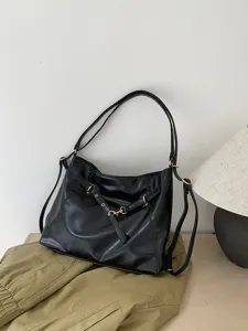 Detail view of black soft leather hobo tote bag with metal buckle and shoulder strap.