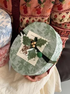 Dettaglio scatola regalo di Natale con motivo retrò verde e decorazione festiva di agrifoglio.