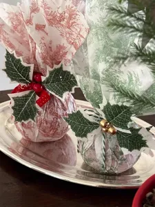 Palline regalo natalizie in carta toile de Jouy con foglie di agrifoglio e bacche rosse.