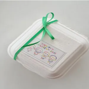 Scatola regalo quadrata bianca con nastro verde e adesivo a tema festa dei bambini per bambini.