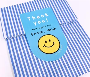 Gros plan de détail du sac cadeau en papier rayé bleu avec un joli autocollant smiley.