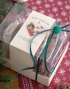 Weihnachten transparente Geschenkschachtel mit Papierbanderole und gruenem Band im Detail