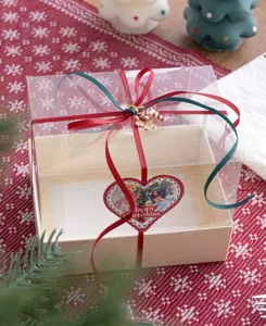 Weihnachtsgeschenk Verpackungsband und transparente Box Detail mit roten grunen Schleifen.