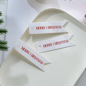 Close-up detail of white Christmas gift hanging tags featuring elegant red merry christmas lettering.