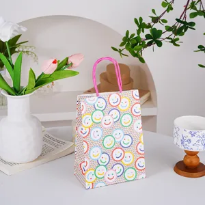 Bonita bolsa de regalo de papel kraft con cara sonriente colorida y asa rosa para postres.