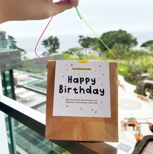 Vista detallada de tarjeta de felicitación cuadrada con bolsa de papel y cordón de color.