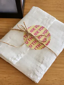 Vue détaillée d'un autocollant de scellement d'emballage cadeau rond avec lettres.