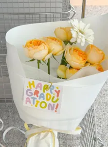 Detailansicht der Abschluss-Grußkarte mit bunter Pastell-Typografie auf weißem Blumenstrauß.