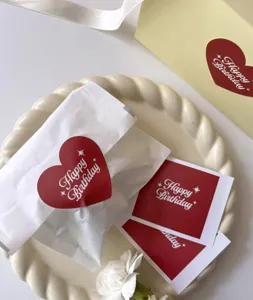 Gros plan détail de stickers de scellage cœur rouge Joyeux Anniversaire et papier cadeau.