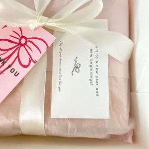 Beautiful gift wrapping set with pink tissue paper white ribbon and thank you cards for presentation.