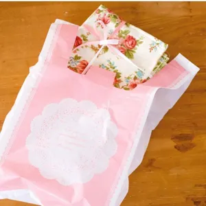 Close up of a large pink plastic vest bag with white lace pattern and floral fabric inside.