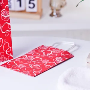 Rote Papiertragetasche Detail mit weißen Herzen und Rosen für Valentinstag Verpackung.