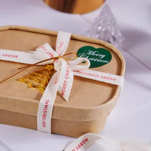 Close-up of Christmas gift box with festive ribbon and gold tree pendant for holiday packaging.