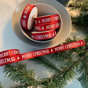 Red Christmas ribbon roll with Merry Christmas print and tree design for gift wrapping.