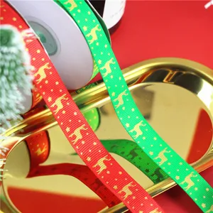 Christmas gift wrapping ribbon detail featuring gold printed elk and stars on red and green satin.