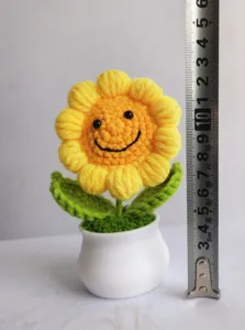 Handmade crochet smiley sunflower potted plant detail view, cute knitted decor for home.