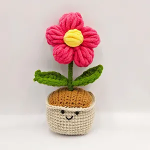 Detail shot of handmade crochet potted flower with cute smiling face pot and vibrant pink petals.