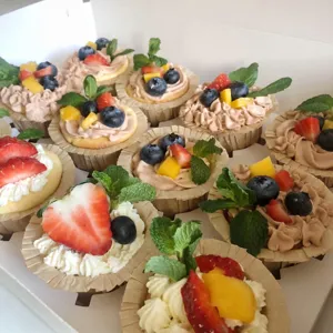Leckere bunte Cupcakes mit frischen Früchten und Creme in Papierförmchen zum Backen.