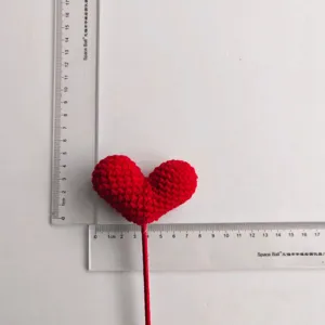Vista dettagliata dell'accessorio fiore a cuore rosso uncinetto, consistenza delicata.