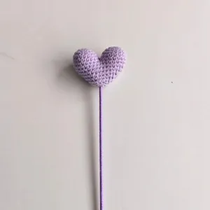 Primo piano dettagliato di uno stelo di fiore di cuore viola all'uncinetto fatto a mano.