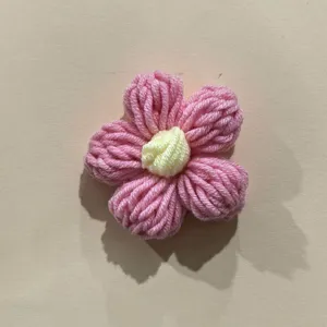 Handmade crochet puff flower detail shot, pink and yellow yarn floral DIY accessory.