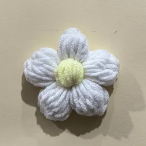 Handcrafted white crochet puff flower detail, adorable yarn DIY accessory for bags.